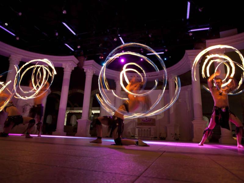 Tanečníci vytvářejí světelné spirály na tmavé podlaze.