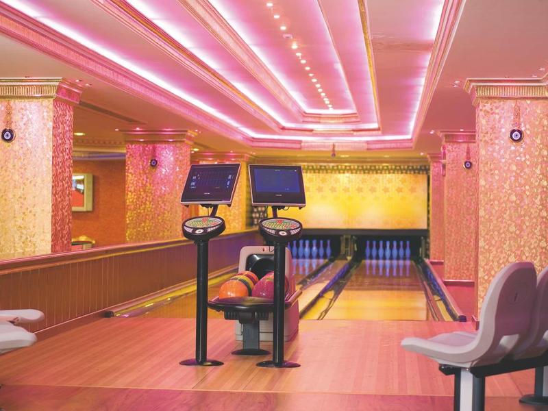 Pláž u bazénu s lehátky a slunečníky pod jasnou oblohou.