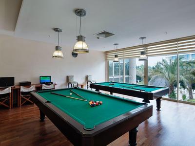 Nowoczesna sala bilardowa z dwoma stołami i widokiem na palmy przez duże okna