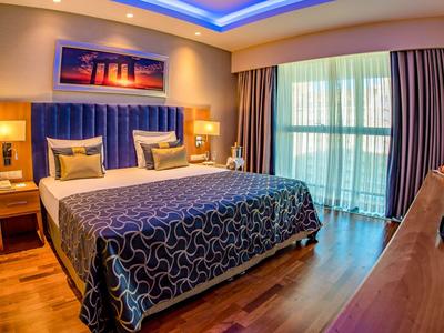 Nowoczesny pokój hotelowy z dużym łóżkiem, niebieskimi akcentami i oknami od podłogi do sufitu