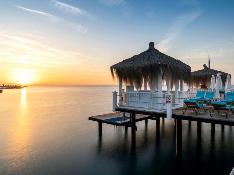 Coucher de soleil sur la mer avec jetée en bois et cabane en chaume sur l'eau