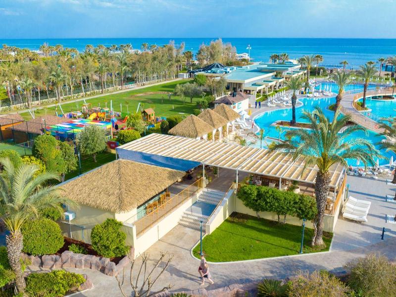 Luchtfoto van een tropisch resort met zwembad, palmbomen en uitzicht op de oceaan.