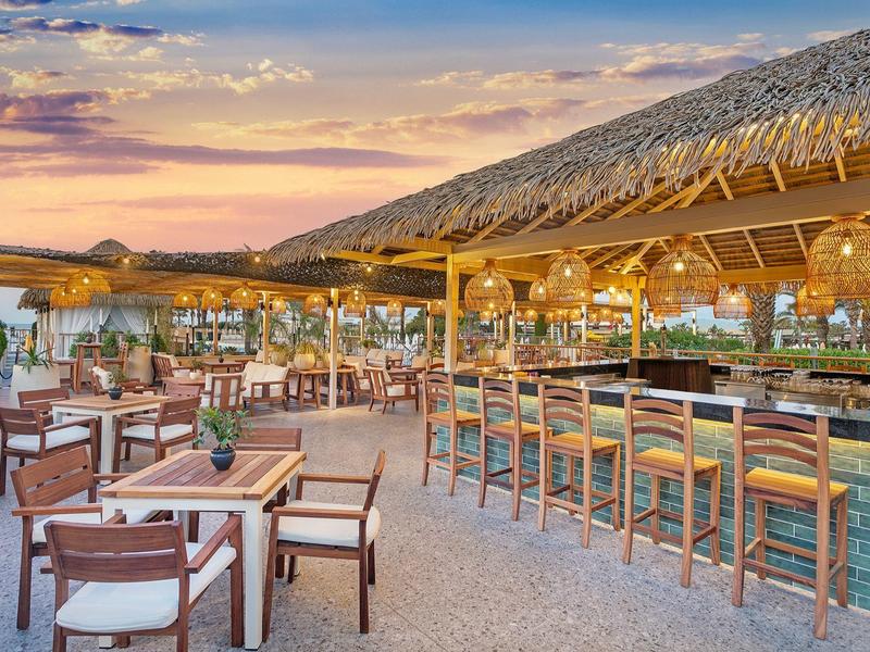 Open strandbar met stoelen en tafels bij zonsondergang