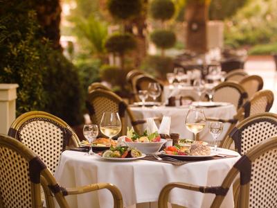 Einladende Außenterrasse mit gedeckten Tischen und Stühlen im warmen Sonnenlicht.