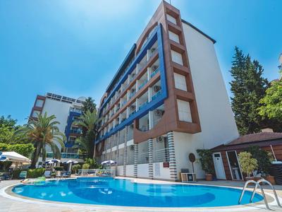 Nowoczesny hotel z basenem, otoczony palmami i czystym niebieskim niebem.