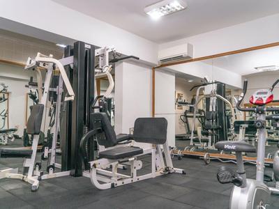 Nowoczesna siłownia z kilkoma urządzeniami treningowymi i dużymi lustrami na ścianach.