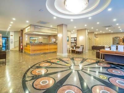 Lichte hotellobby met decoratieve marmeren vloer en receptie op de achtergrond.