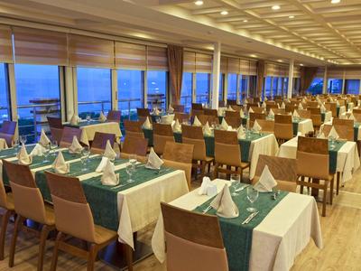 Grote eetzaal met gedekte tafels en uitzicht op zee