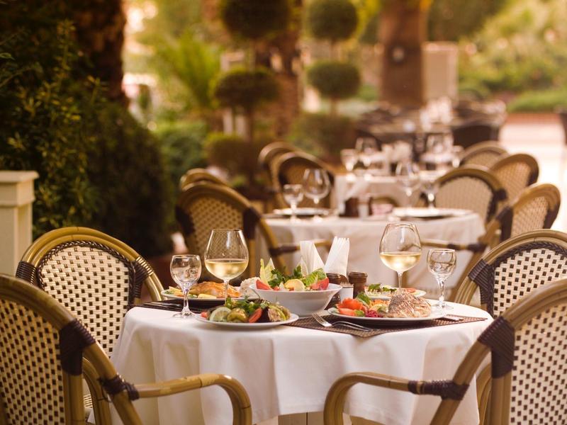Einladende Außenterrasse mit gedeckten Tischen und Stühlen im warmen Sonnenlicht.