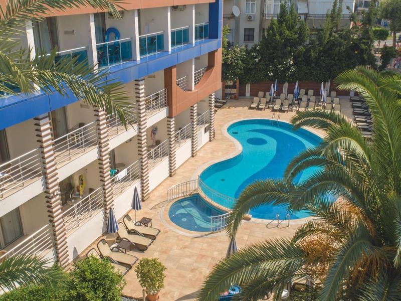 Hotel mit blauem, geschwungenem Pool, Liegestühlen und Palmen in sonniger Gartenanlage.