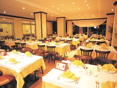 Gut beleuchteter, eleganter Speisesaal mit weiß gedeckten Tischen und Holzstühlen.