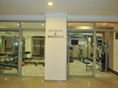 Sala fitness e massaggi con vari attrezzi da palestra dietro porte scorrevoli in vetro.