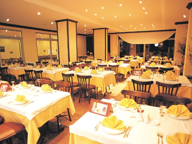 Gut beleuchteter, eleganter Speisesaal mit weiß gedeckten Tischen und Holzstühlen.