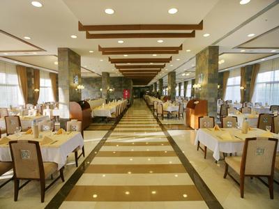 Velká elegantní jídelna s prostřenými stoly a širokou střední uličkou.