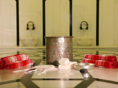 Tradiční turecký hammam s mýdlem, houbami a červenými ručníky na mramorových dlaždicích.