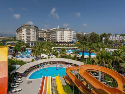 Großes Hotel mit mehreren Pools, Wasserrutschen in Orange, Gelb und Blau, Palmen und Liegestühlen.