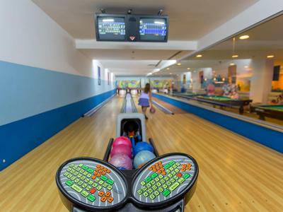 Vista di una pista da bowling con bocce colorate e due schermi sul soffitto.