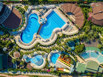 Vista aerea di una grande piscina dell'hotel con più vasche e paesaggio verde circostante.