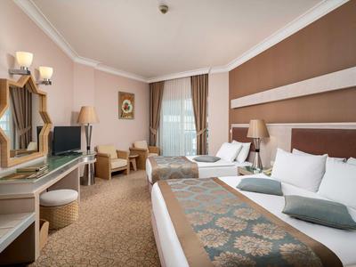 Camera luminosa con due letti, elegante scrivania e area salotto in un hotel.