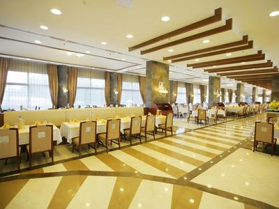 Ampia ed elegante sala da pranzo con lunghi tavoli e molte sedie, illuminazione luminosa.