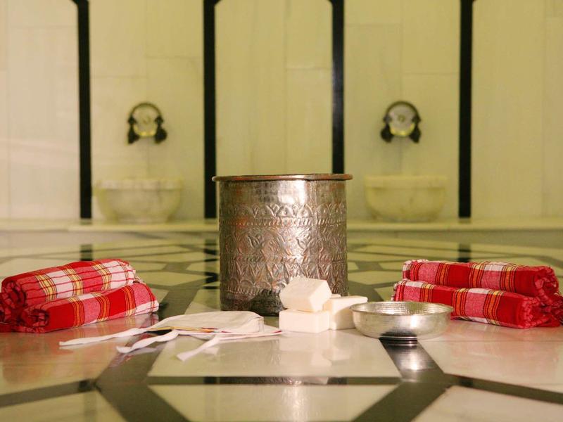 Tradiční turecký hammam s mýdlem, houbami a červenými ručníky na mramorových dlaždicích.