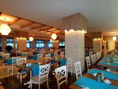 Großes gewerbliches Restaurant mit weißen Stühlen, blauen Tischdecken und warmem Deckenlicht.