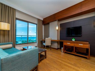 Modern eingerichtetes Wohnzimmer mit Sofa, Schreibtisch, großem Fenster und Meerblick.