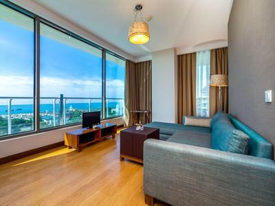 Modernes Wohnzimmer mit großen Panoramafenstern, grauem Sofa, braunem Couchtisch und Meerblick.