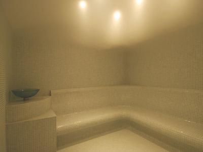 Helle, minimalistische Sauna mit hellen Wänden, Eckbank und einer Schale als Dekoration.