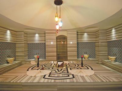 Großer traditioneller türkischer Hamam mit gemusterten Wänden und zentralem Marmortisch.