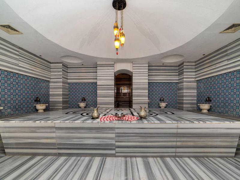 Luxe marmeren Turkse bad met gestreepte muren en centrale loungeplatform.