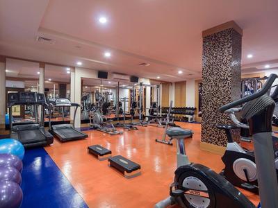 Moderner Fitnessraum mit Laufbändern, Hanteln und Trainingsgeräten in einem Hotel.