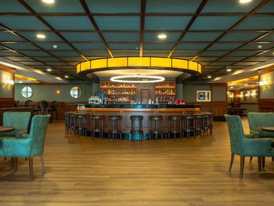 Bar elegante de hotel con barra circular e iluminación moderna en tonos cálidos.