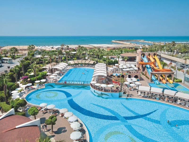 Gran piscina del hotel con toboganes y vista al mar en un día soleado.