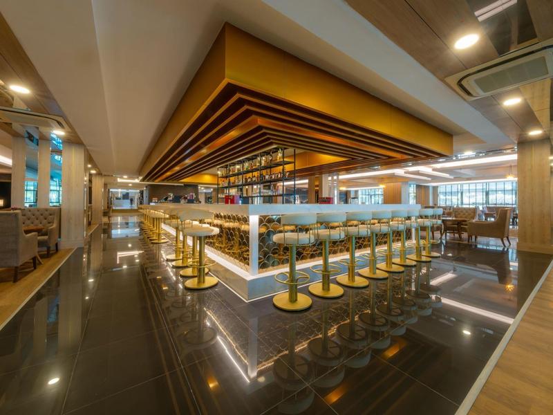 Interior de un restaurante moderno con taburetes dorados y detalles en madera.