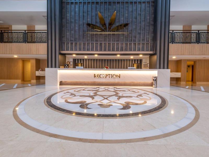 Gran recepción de hotel con mostrador elegante y suelo de mármol decorativo.
