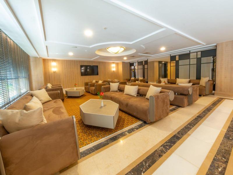 Amplia sala moderna de hotel con cómodos sillones y revestimientos de madera clara.