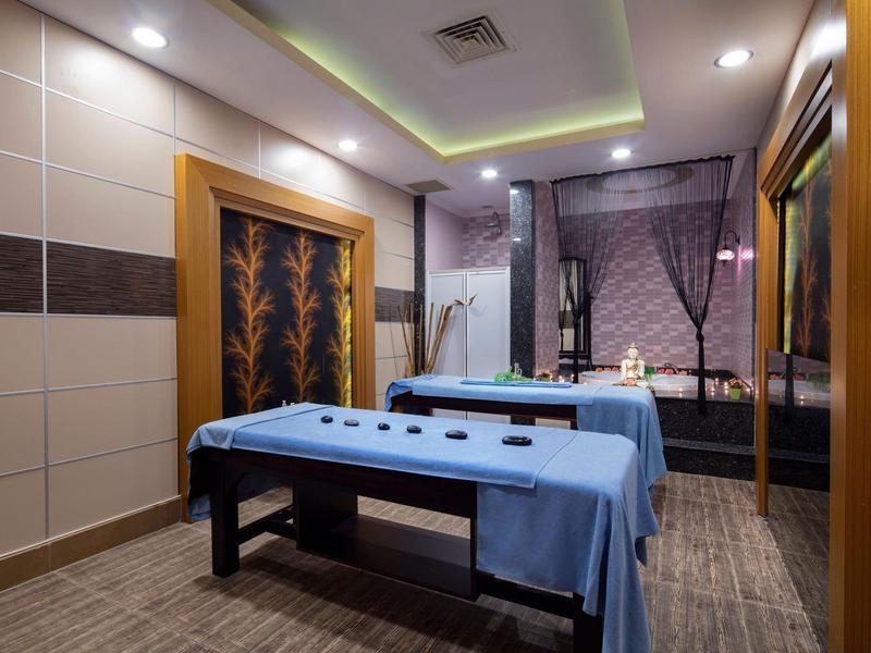 Sala de masajes moderna con dos camillas, iluminación relajante y paneles de madera decorativos.