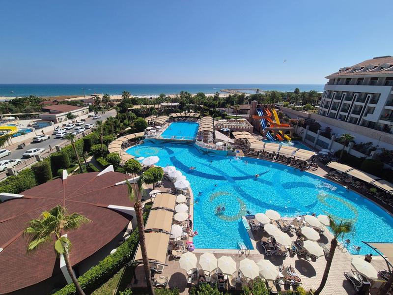 Gran piscina de hotel con sombrillas y tumbonas, cerca de la playa bajo un cielo azul.