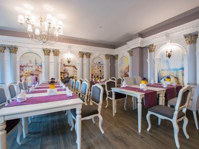 Elegante comedor con mesas blancas, sillas y candelabros en un hotel clásico.