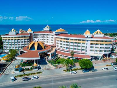Großes Hotelgebäude an einer Küstenstraße mit Meerblick und blauem Himmel.