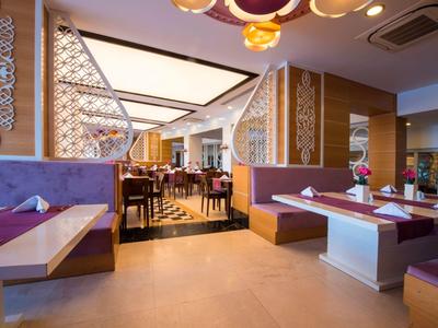 Modern eingerichteter Restaurantbereich mit Tischen, Stühlen und dekorativen Wandelementen.