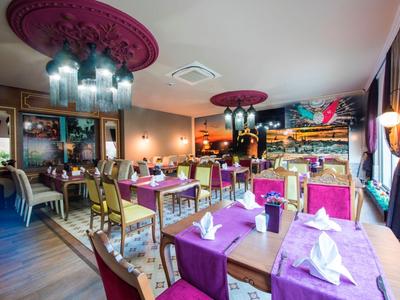 Elegantes Restaurant mit bunten Stühlen, dekorativen Kronleuchtern und gedeckten Tischen.