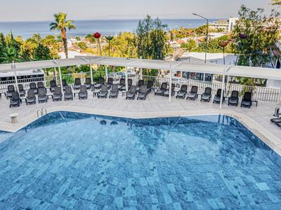 Piscina all'aperto moderna con lettini e vista sul mare e palme sullo sfondo.