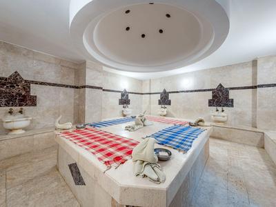 Interno di un hammam in marmo con due asciugamani colorati su una lastra riscaldata.