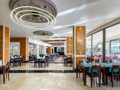 Ampia sala da pranzo luminosa con arredamento moderno e grandi finestre in un hotel.