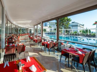 Terrazza con tavoli apparecchiati e vista sulla piscina di un hotel.