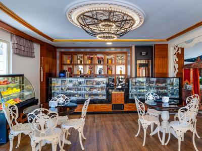 Caffè luminoso con tavoli in metallo bianco e grandi vetrine piene di dolci.