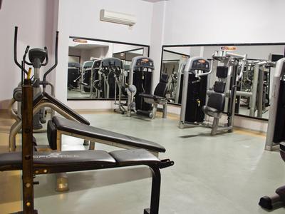 Salle de sport moderne avec équipements et grands miroirs au mur.