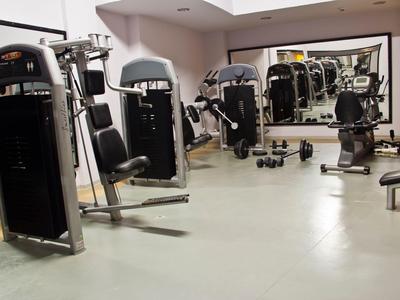 Salle de sport lumineuse avec diverses machines de musculation et grands miroirs au mur.